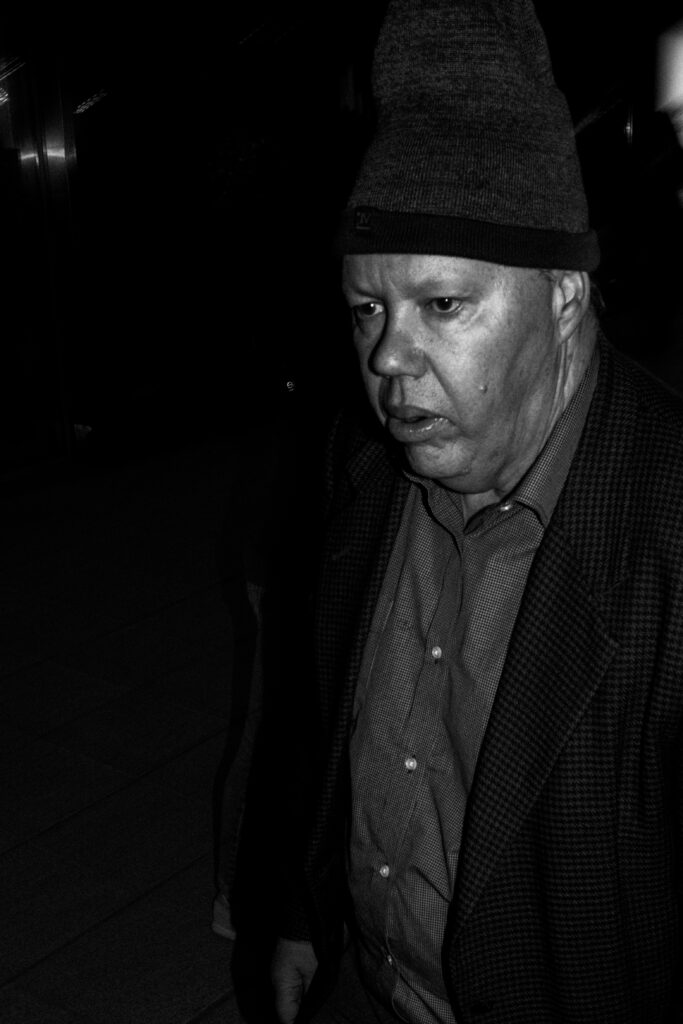 A man in a knitted hat and tweed jacket walking through a dark station